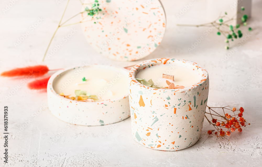 Holders with candles and flowers on white background