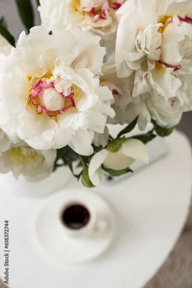 Vase of white peonies on table in room