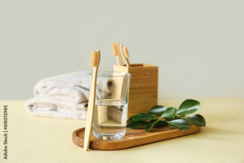 Bamboo tooth brush and glass of water in bathroom