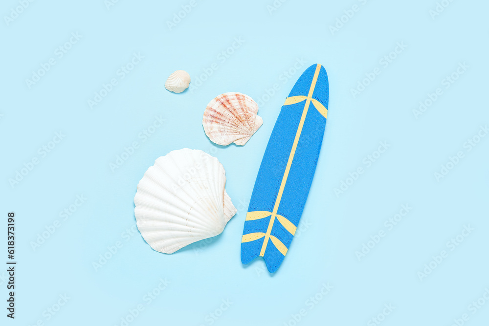 Mini surfboard with seashells on blue background