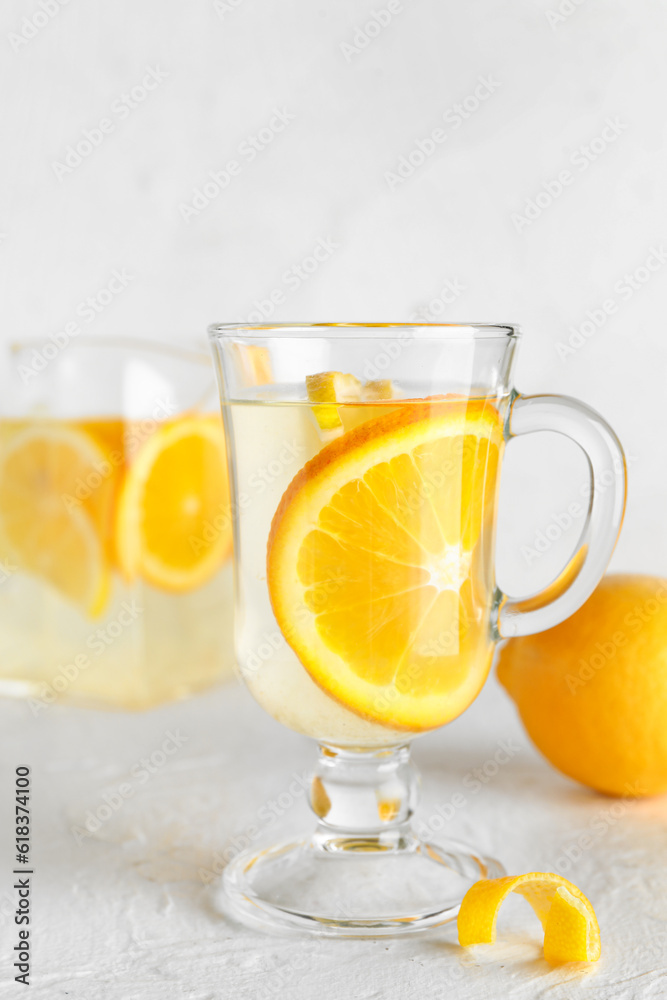 Glass cup of infused water with lemon on light background