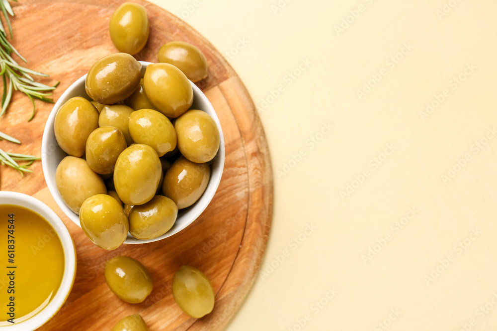 Bowls with ripe olives and oil on yellow background