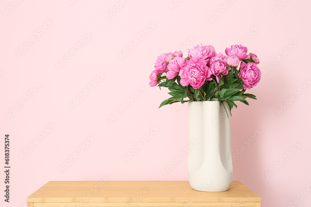 Vase of pink peonies on shelving unit near color wall