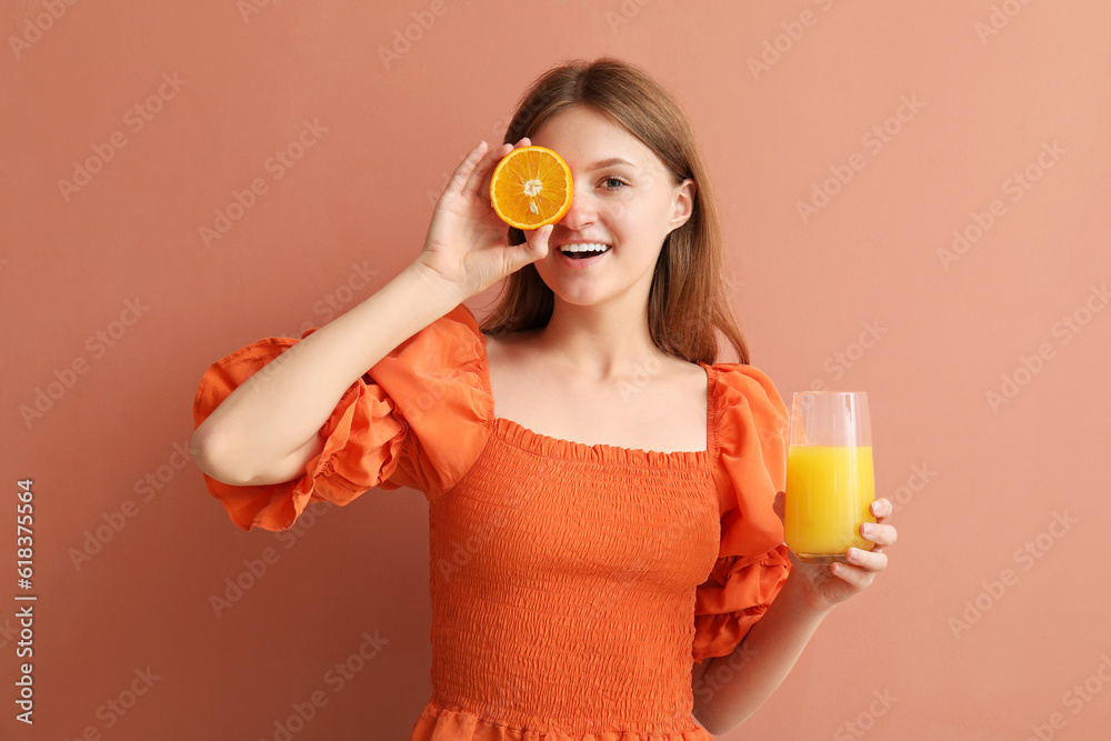 Teenage girl with orange and glass of juice on pink background