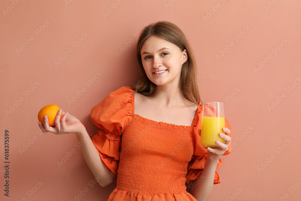 Teenage girl with orange and glass of juice on pink background