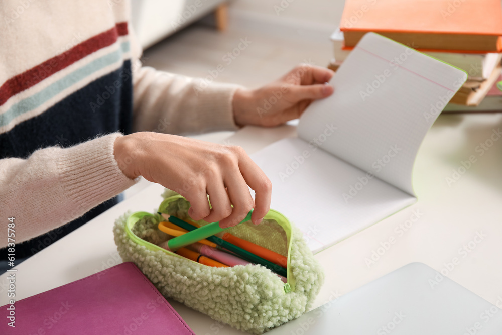 Female student with pencil case at table, closeup