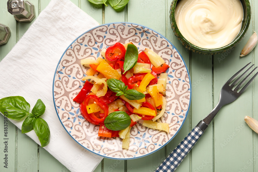 Plate with tasty grilled peppers and sauce on green wooden background