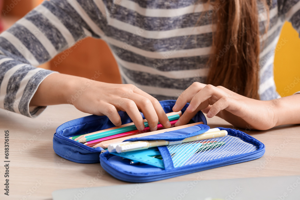 Little girl with pencil case at table, closeup