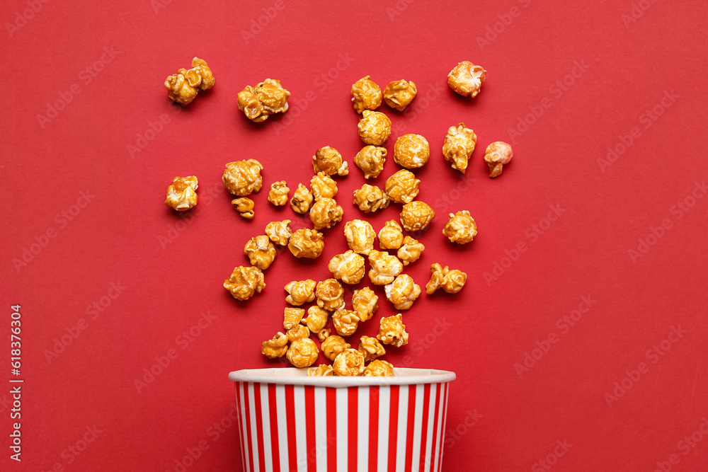 Bucket with tasty popcorn on red background