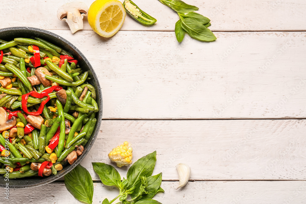 Frying pan with different vegetables on light wooden background