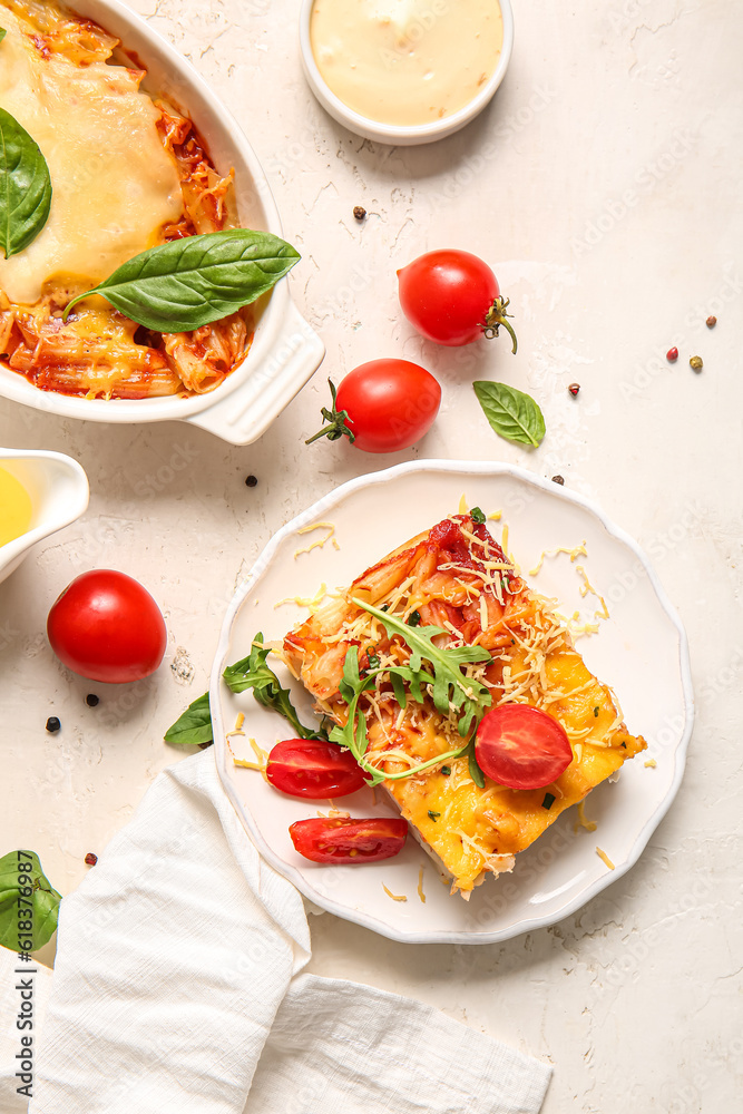 Baking dish and plate of pasta with tomato sauce on white background