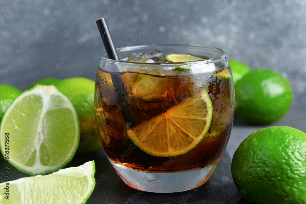 Glass of cold Cuba Libre cocktail on grey background