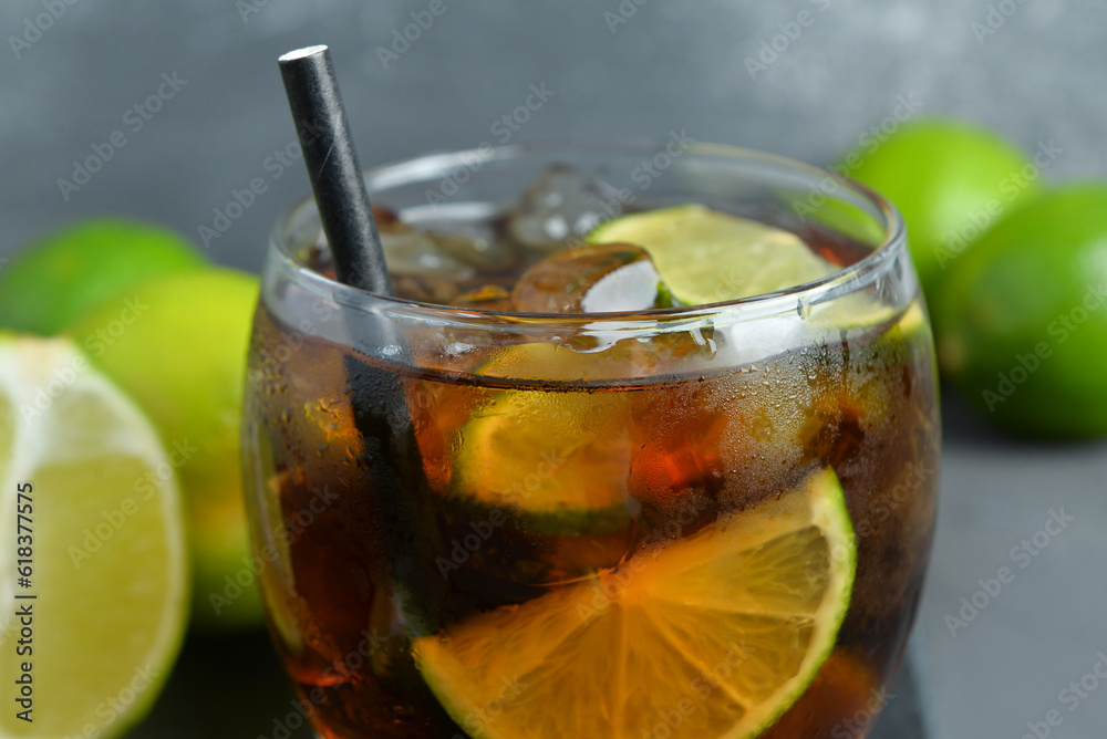 Glass of cold Cuba Libre cocktail on grey background