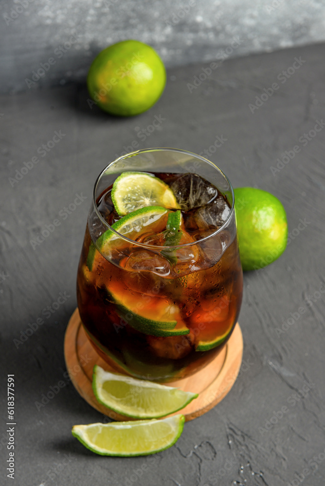 Glass of cold Cuba Libre cocktail on grey background