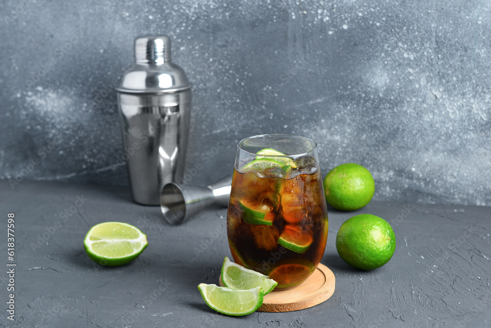 Glass of cold Cuba Libre cocktail on grey background