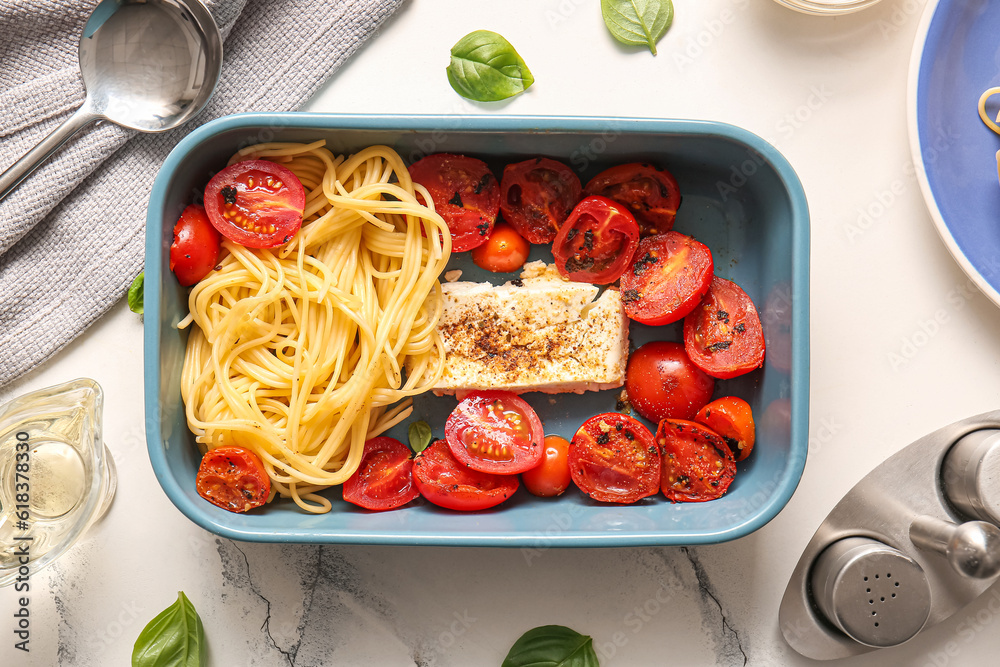 Baking dish of tasty pasta with tomatoes and feta cheese on white marble background