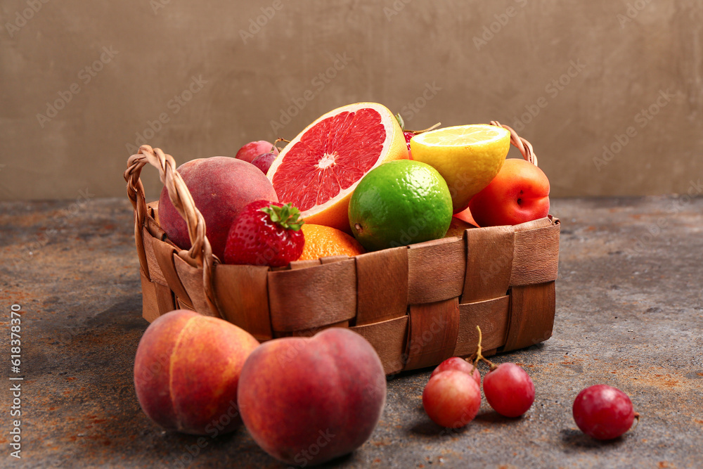 Wicker basket with different fresh fruits on dark table