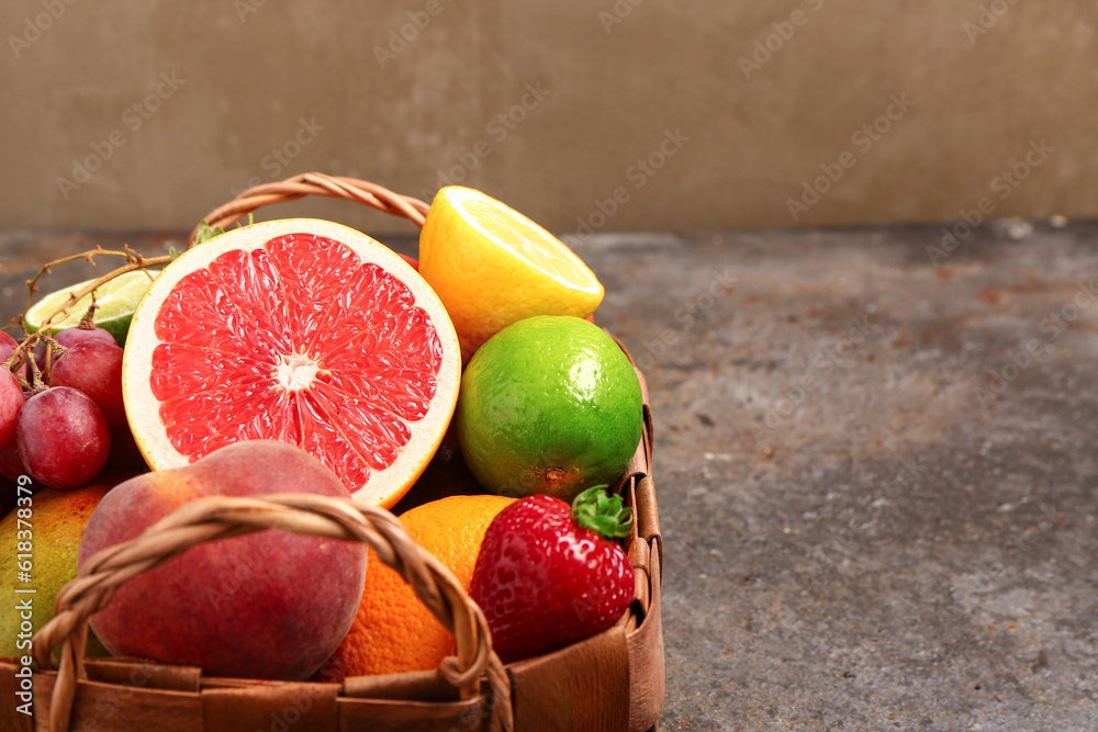 Wicker basket with different fresh fruits on dark table