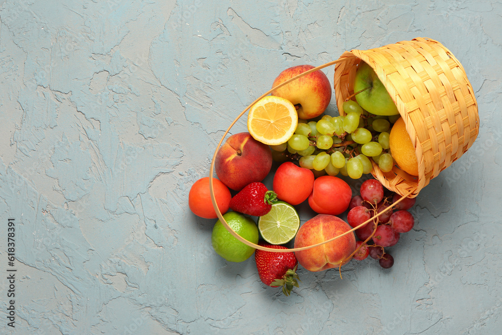 Wicker basket with different fresh fruits on blue background