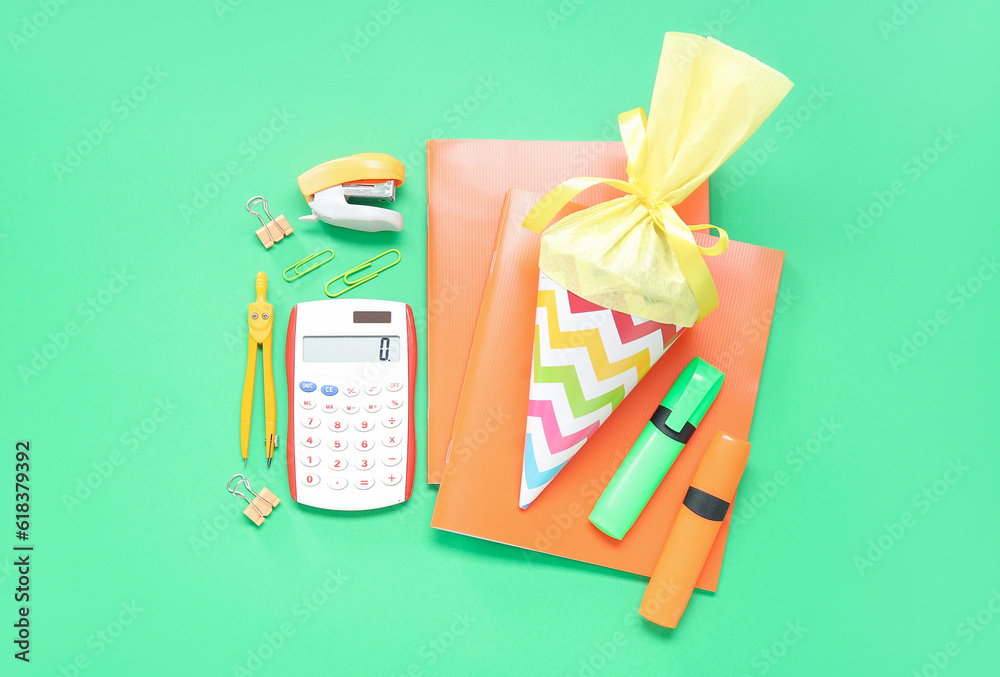 Yellow school cone with different stationery on green background