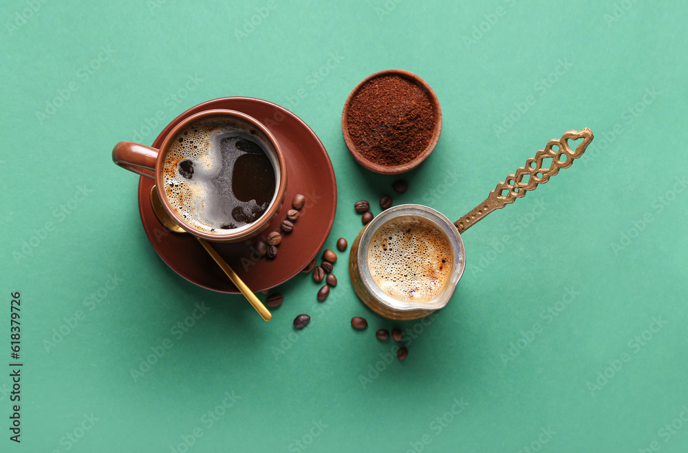 Cezve and cup decorated with coffee beans on green background