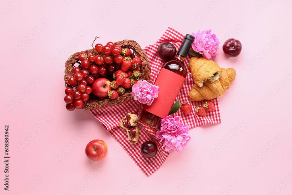 Composition with tasty food for picnic, bottle of wine and peony flowers on pink background