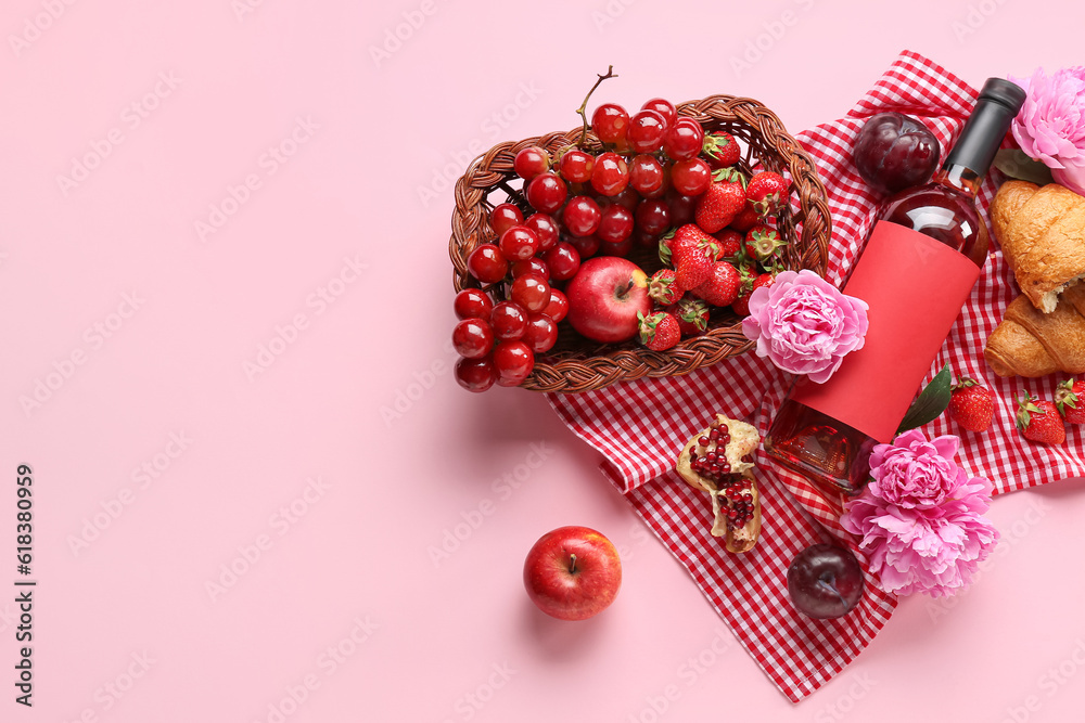 Composition with tasty food for picnic, bottle of wine and peony flowers on pink background