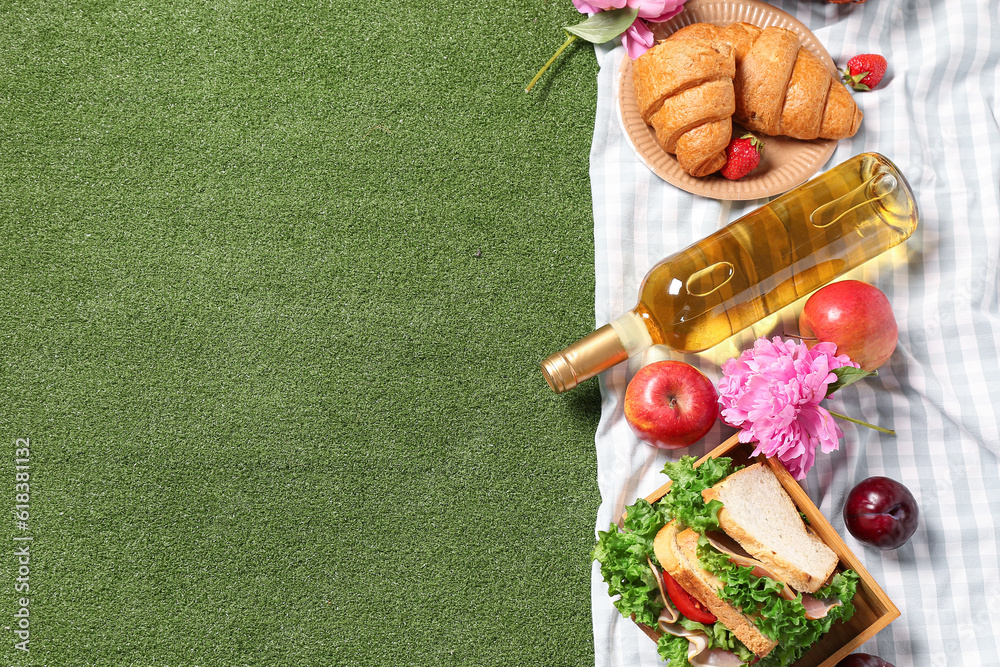 Composition with tasty food for picnic, wine and peony flowers on green background