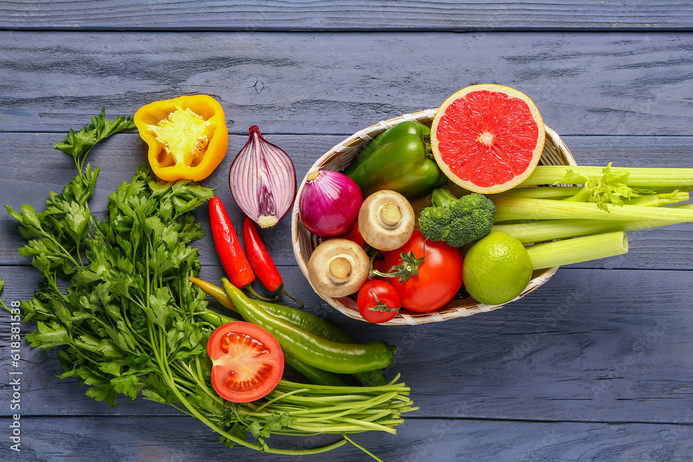 Basket with fresh ripe vegetables on blue wooden background