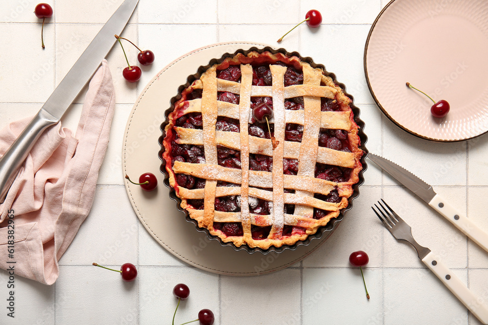 Baking dish with tasty cherry pie on white tile background