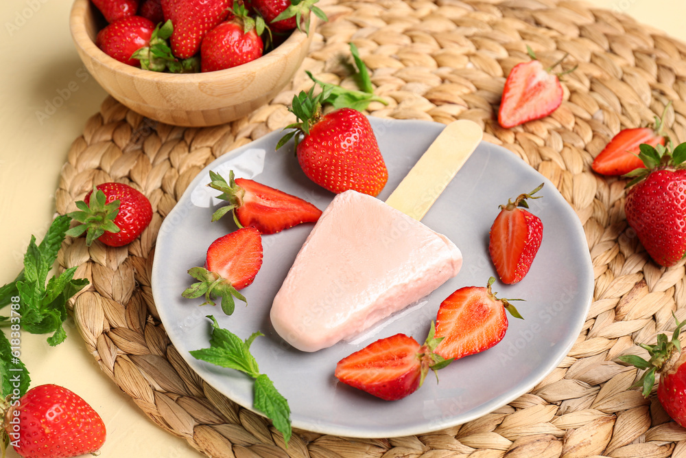 Plate with sweet strawberry ice-cream popsicle and bowl of berries on yellow background