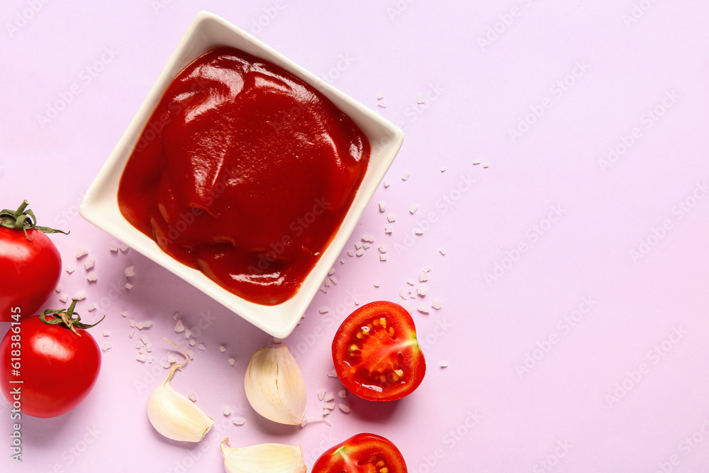 Bowl with tomato paste and fresh vegetables on lilac background