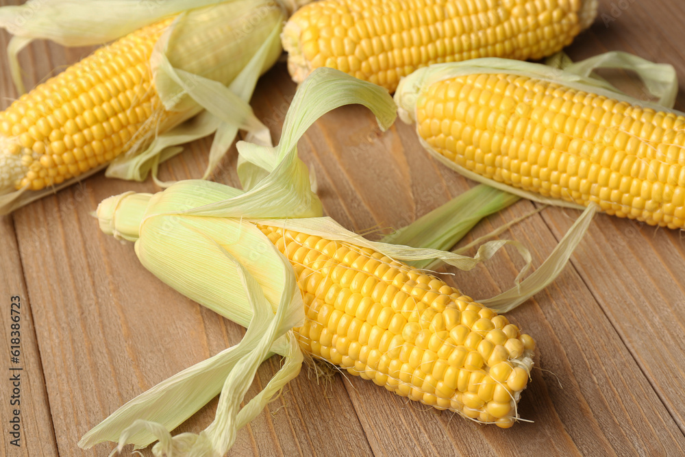 Fresh corn cobs on wooden background