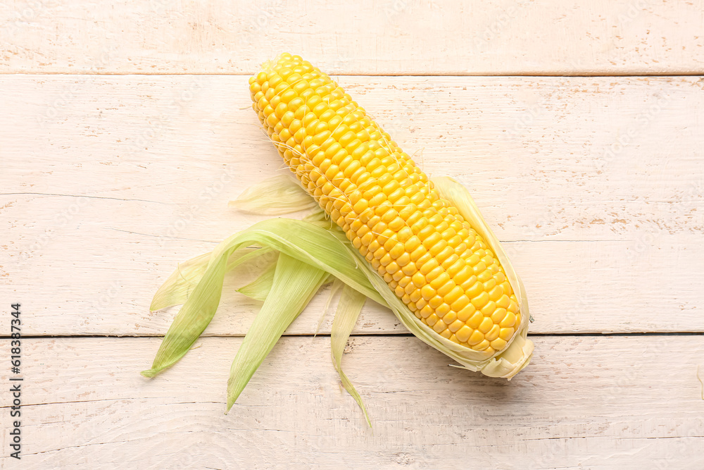 Fresh corn cob on white wooden background