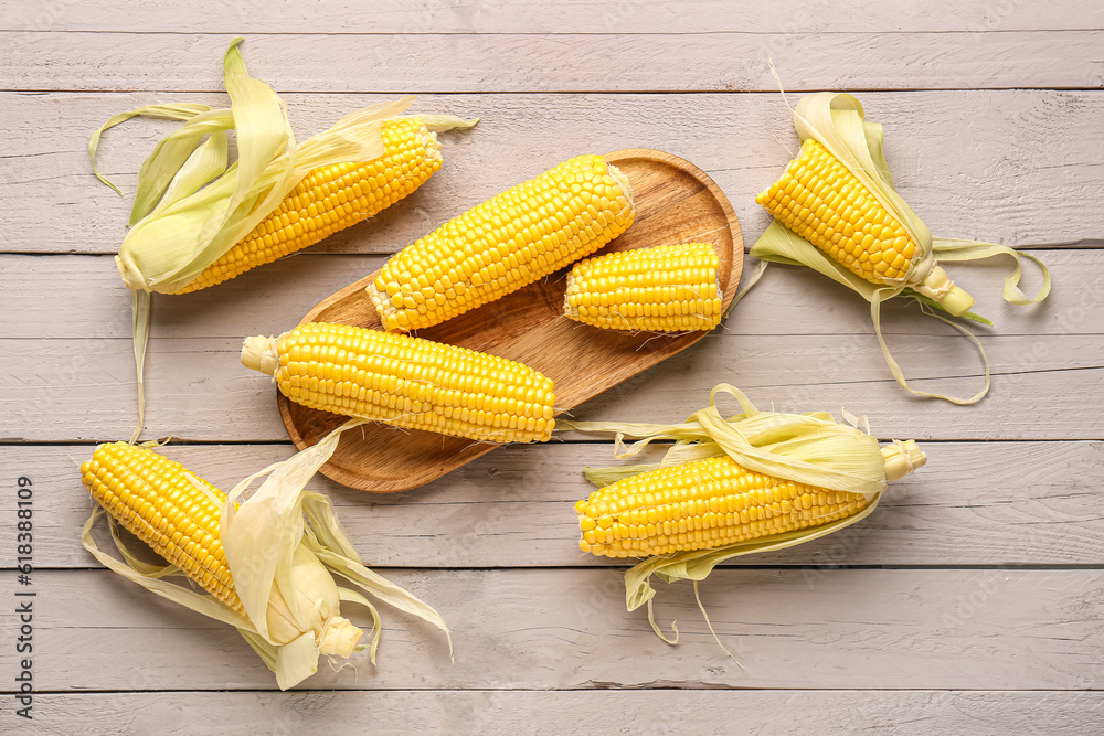 Board with fresh corn cobs on grey wooden background