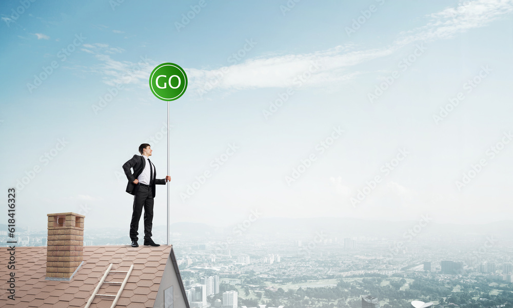 Businessman in suit on house top with ecology concept signboard. Mixed media