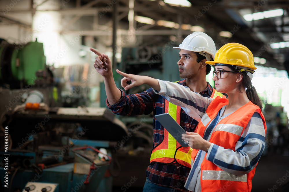 Caucasian woman programmer engineer and indian man Technician operator machine is working in factory