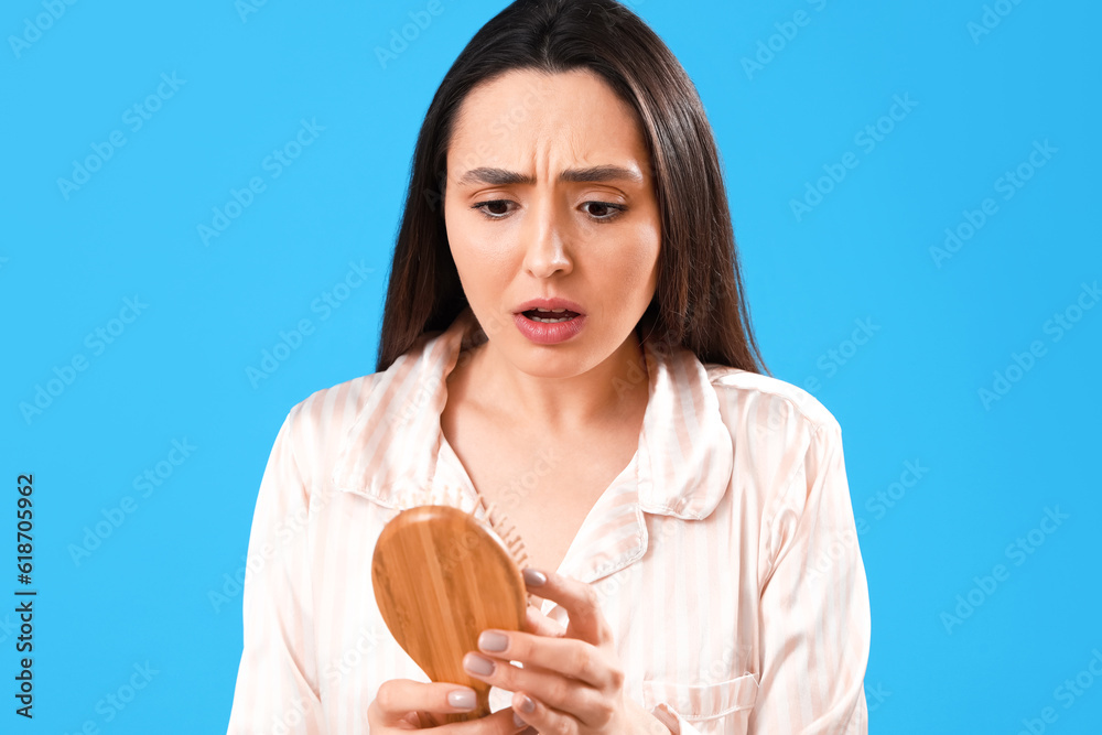 Worried young woman with hair loss problem on blue background