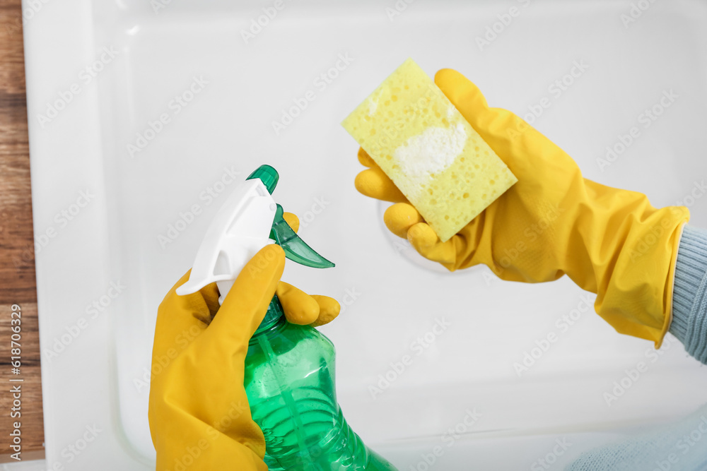 Woman cleaning white sink with sponge, baking soda and sprayer, closeup