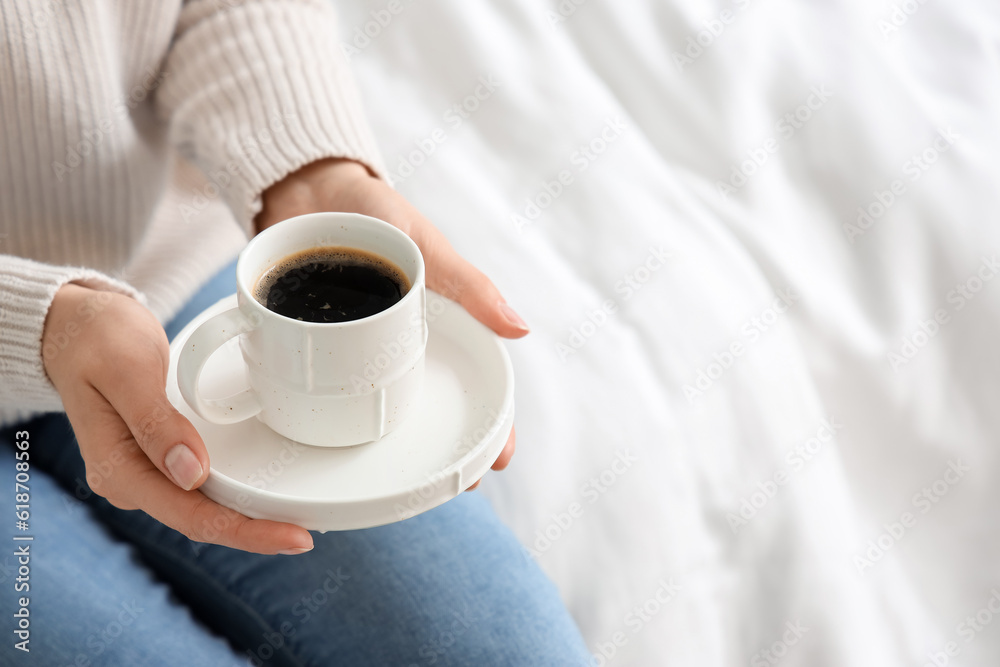 Woman holding saucer with cup of coffee, closeup