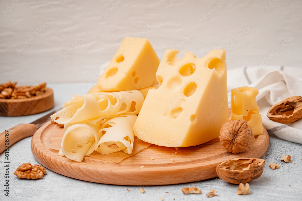 Board with pieces of Swiss cheese and walnut on white table