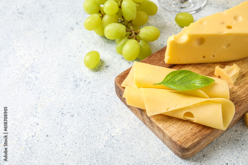 Wooden board with tasty Swiss cheese on light background