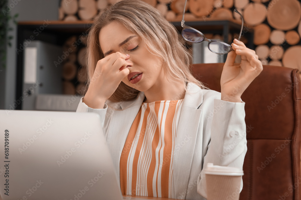 Tired businesswoman with stylish eyeglasses in office