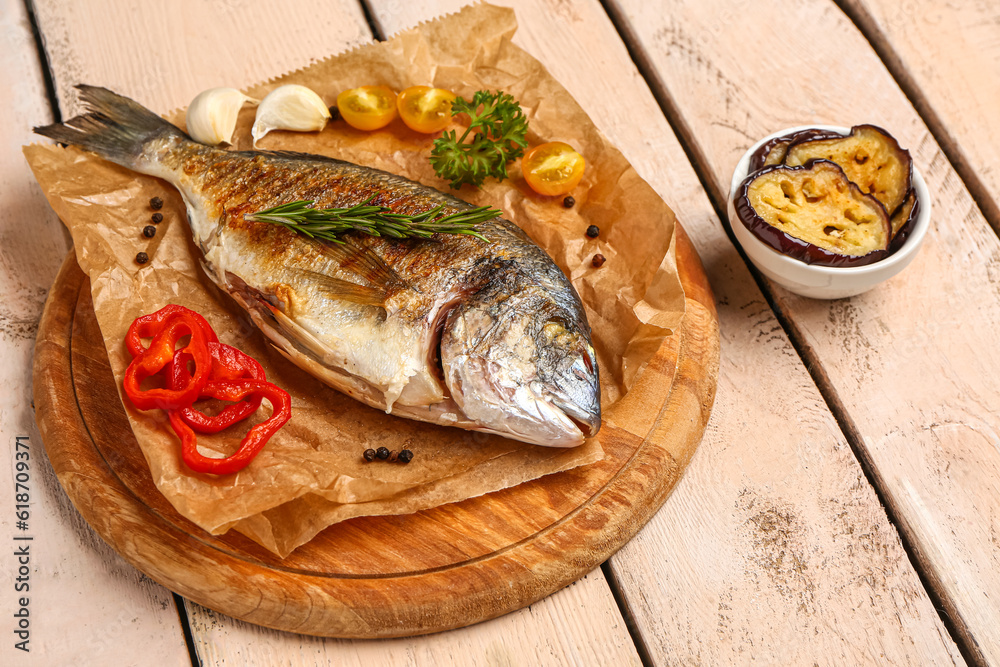 Board with tasty grilled dorado fish on light wooden background