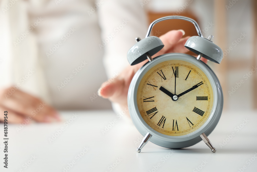 Businesswoman touching alarm clock on table, closeup. Time management concept