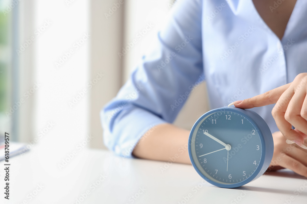 Businesswoman touching alarm clock on table, closeup. Time management concept