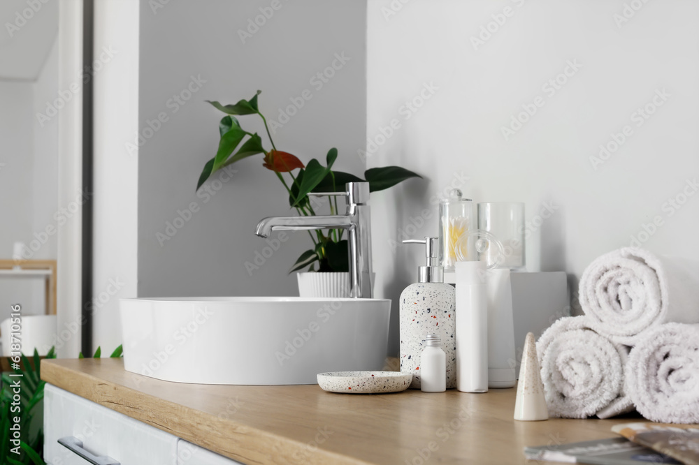 Sink bowl and bath accessories on wooden counter in bathroom