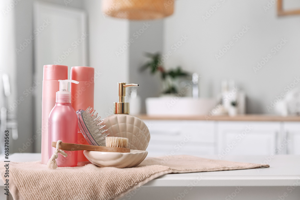 Brushes, soap dispenser and bath accessories on table in bathroom, closeup