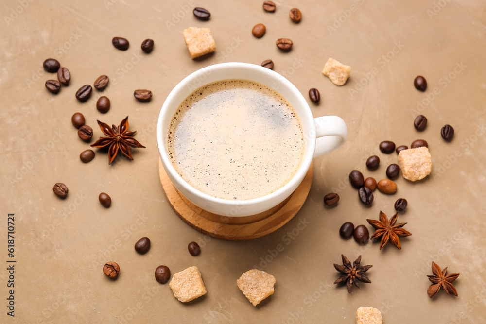 Cup of hot espresso with star anise and coffee beans on brown background