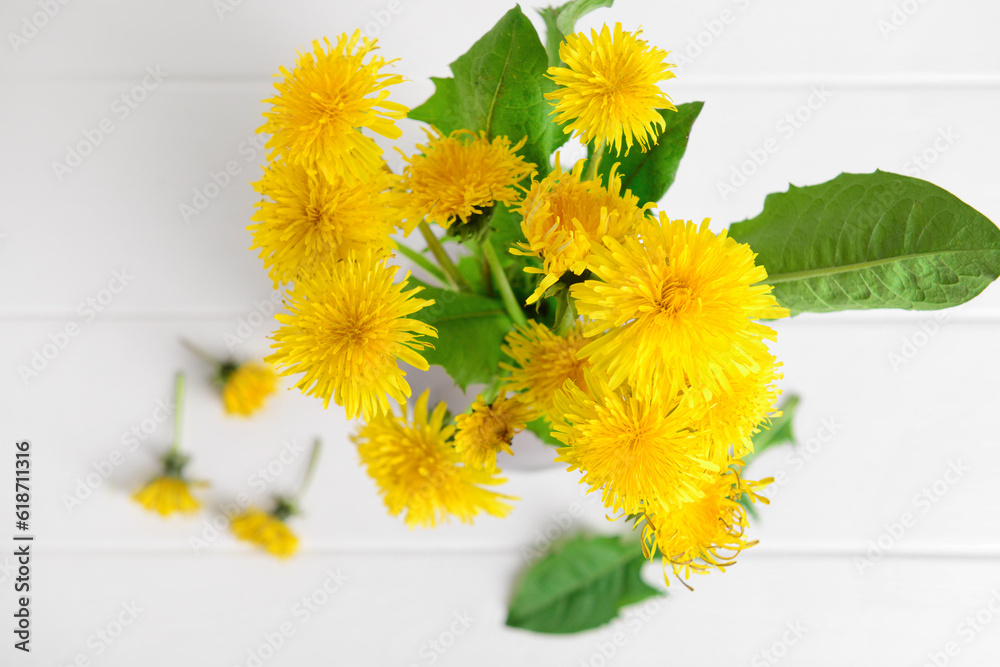 Yellow dandelion flowers on light wooden background